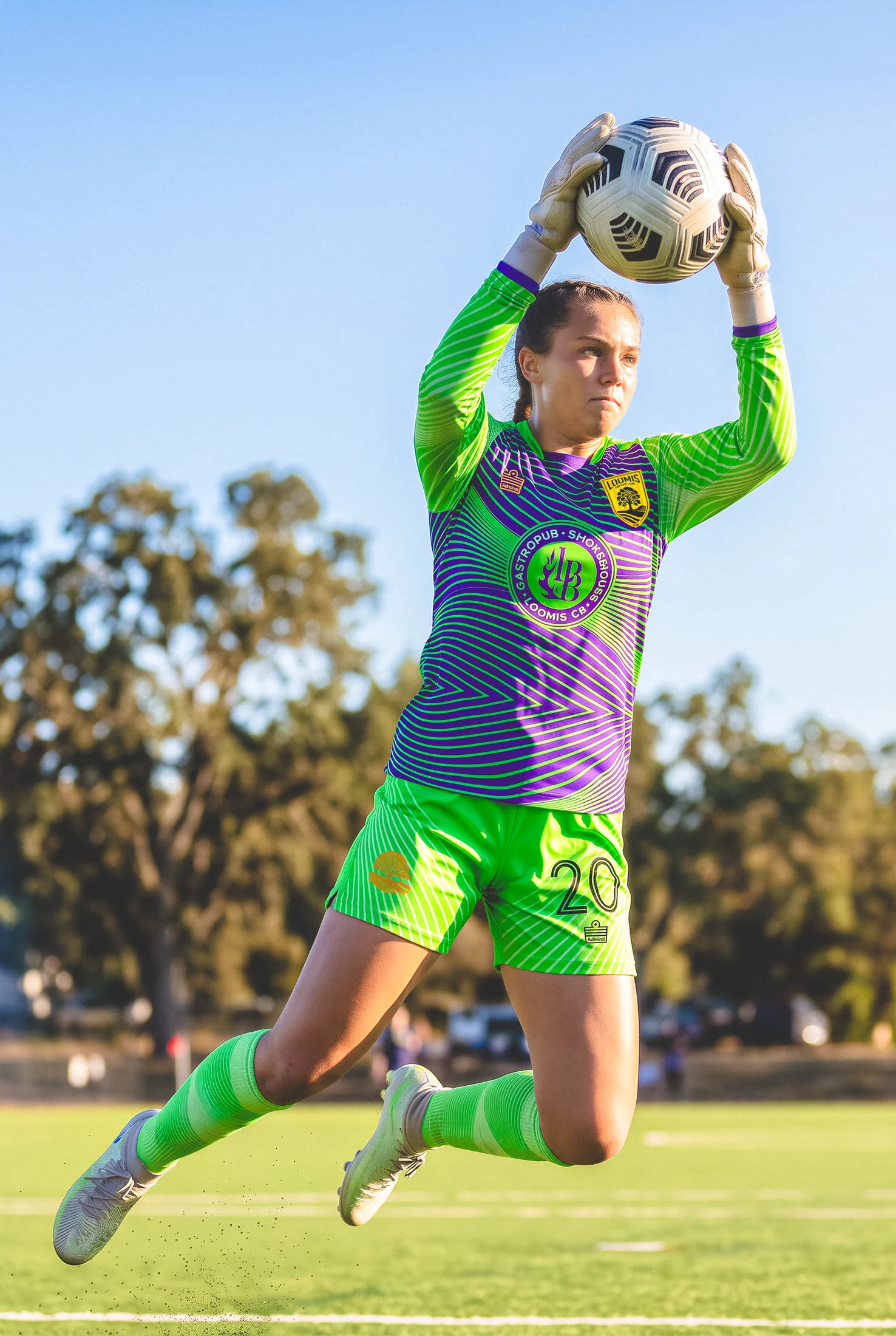 Loomis goalkeeper making a high save in green and purple