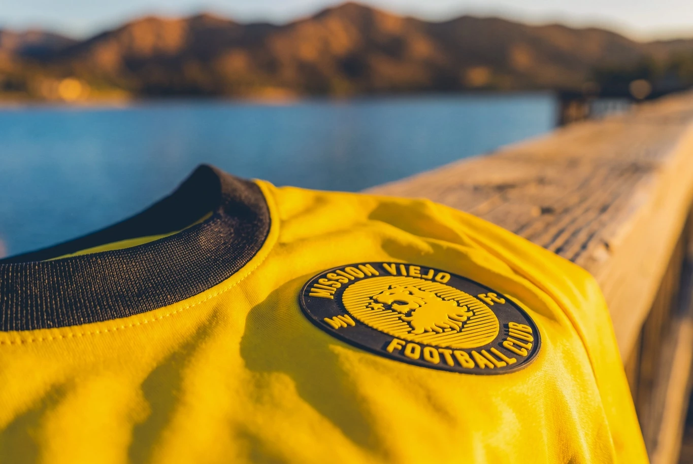 Close-up of the Mission Viejo FC lion badge on the gold home shirt